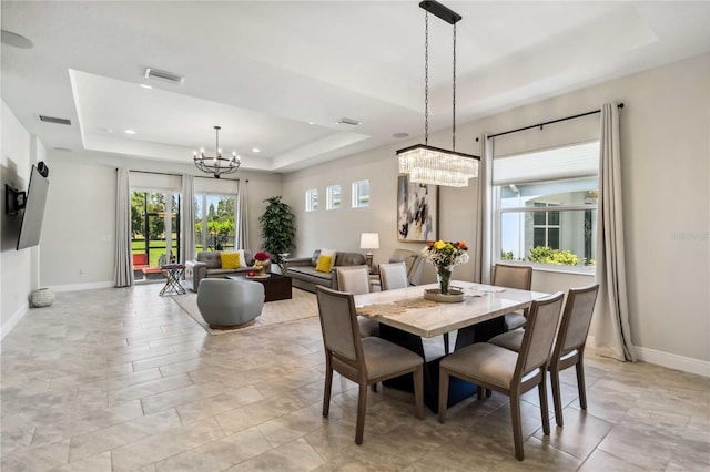 dining space with a raised ceiling and a notable chandelier