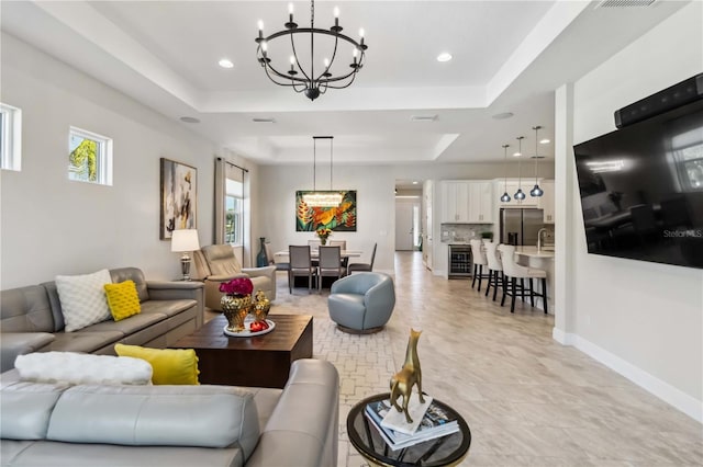 living room featuring an inviting chandelier and a tray ceiling