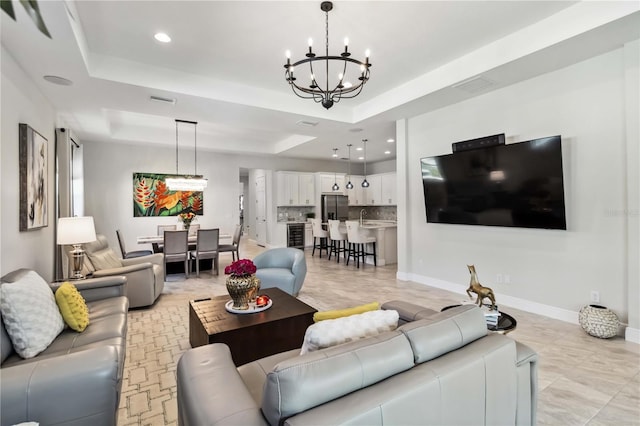 living room featuring sink, an inviting chandelier, and a tray ceiling