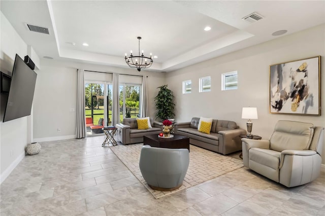 living room featuring a raised ceiling and a notable chandelier