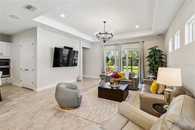 living room with an inviting chandelier and a tray ceiling