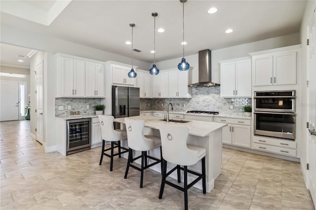 kitchen with white cabinetry, sink, wall chimney range hood, and wine cooler