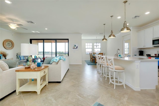 living room featuring crown molding, sink, and ceiling fan