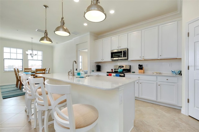 kitchen featuring white cabinetry, appliances with stainless steel finishes, a center island with sink, and pendant lighting