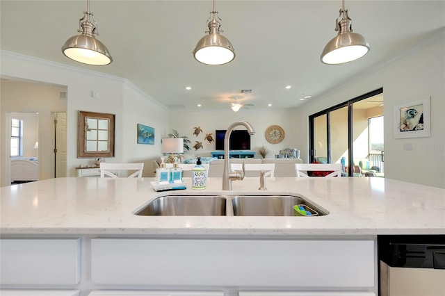 kitchen featuring light stone counters, decorative light fixtures, and a center island with sink