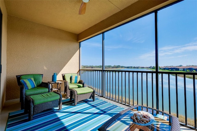 sunroom featuring a water view and ceiling fan