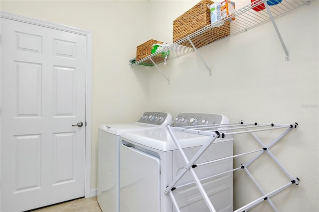 clothes washing area featuring light tile patterned flooring and washer and clothes dryer