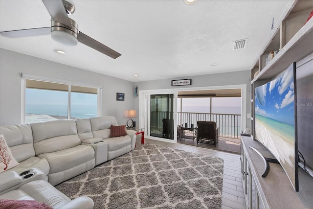 living room with hardwood / wood-style flooring, a textured ceiling, and ceiling fan