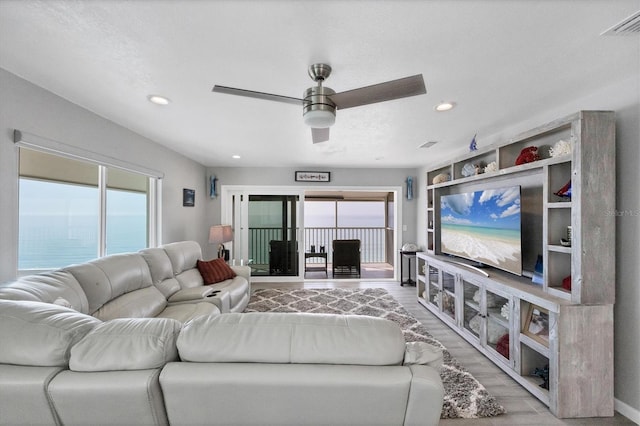 living room with a water view, ceiling fan, and light hardwood / wood-style flooring