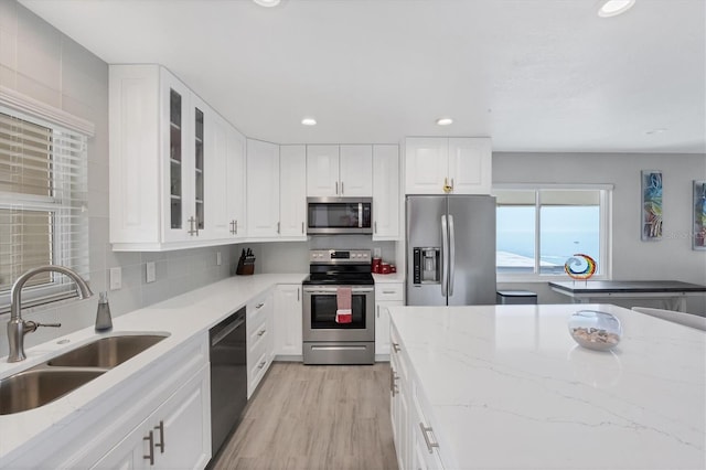 kitchen with white cabinetry, appliances with stainless steel finishes, light stone countertops, and sink