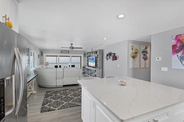 kitchen featuring a center island, white cabinets, light stone counters, and stainless steel fridge with ice dispenser