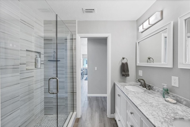 bathroom with walk in shower, wood-type flooring, and vanity