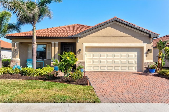10466 Medjool Dr, Venice, FL 34293 - view of front of property featuring stone siding, a tiled roof, decorative driveway, a garage, and stucco siding