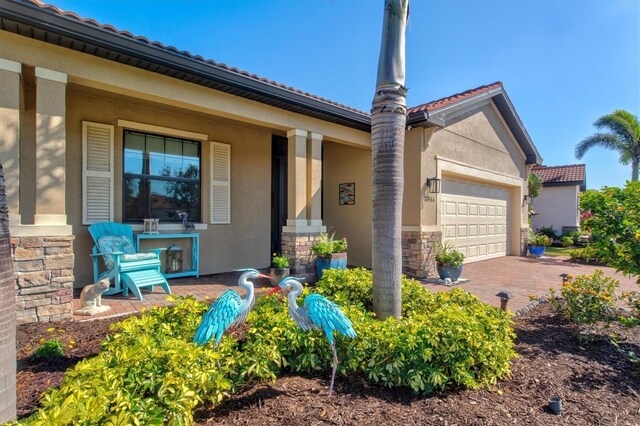 10466 Medjool Dr, Venice, FL 34293 - view of front of house featuring stone siding, covered porch, a garage, and stucco siding