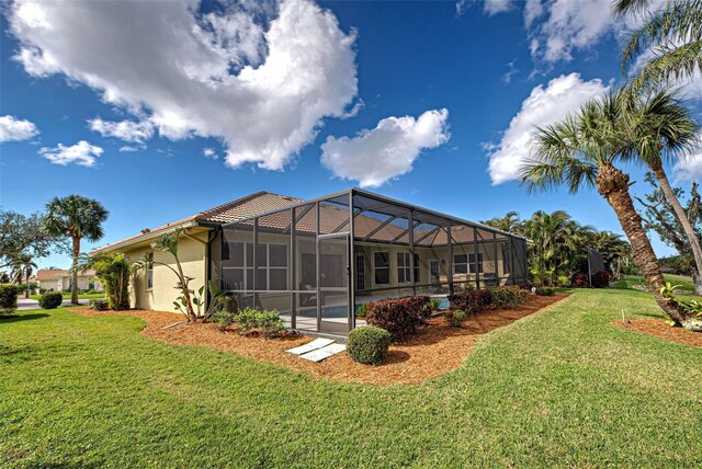 408 Otter Creek Dr, Venice, FL 34292 - rear view of house with a lawn, stucco siding, and glass enclosure