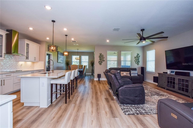 living room featuring sink, ceiling fan, and light hardwood / wood-style flooring