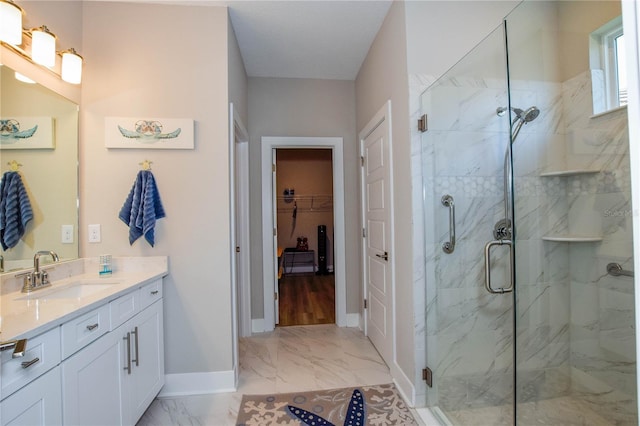 bathroom featuring a shower with door and vanity