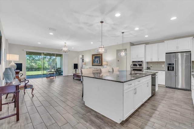 kitchen featuring white cabinetry, appliances with stainless steel finishes, an island with sink, and pendant lighting