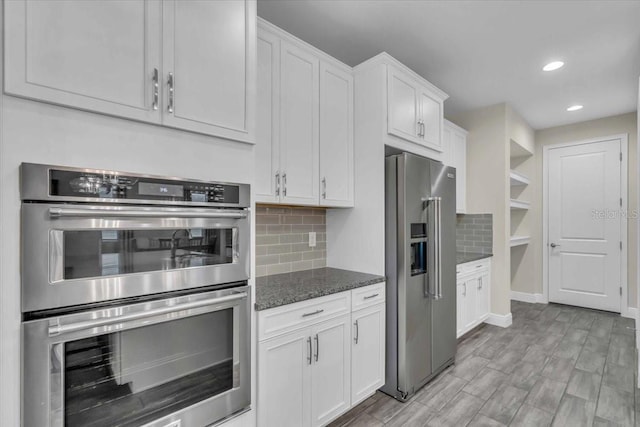 kitchen featuring tasteful backsplash, white cabinetry, appliances with stainless steel finishes, and dark stone counters