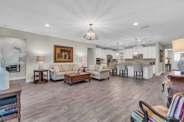 living room featuring sink, a chandelier, and light hardwood / wood-style floors