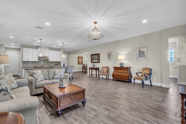 living room featuring an inviting chandelier, sink, and wood-type flooring