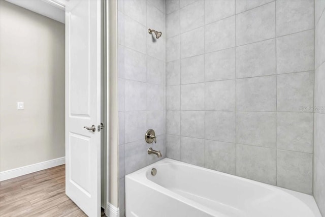 bathroom with hardwood / wood-style floors and tiled shower / bath