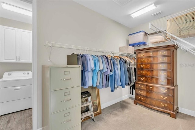 spacious closet featuring washer / dryer and light carpet