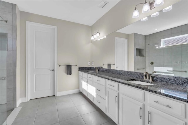 bathroom with tiled shower, vanity, and tile patterned flooring