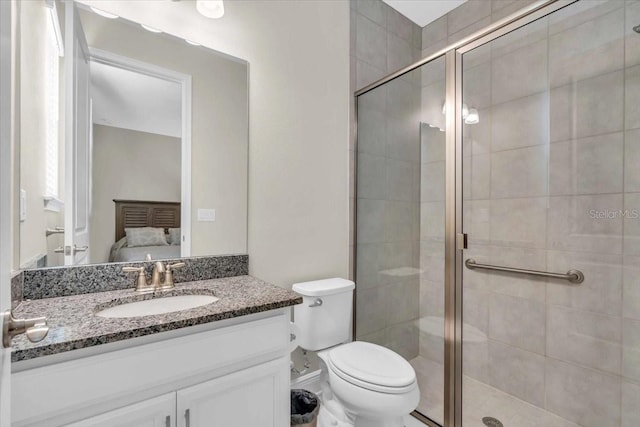 bathroom featuring vanity, a shower with shower door, and toilet