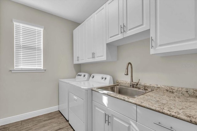 washroom with cabinets, sink, washing machine and dryer, and light wood-type flooring