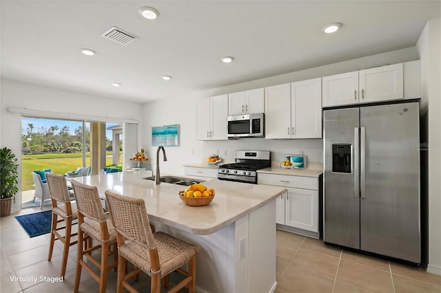 kitchen featuring a breakfast bar, sink, white cabinetry, an island with sink, and stainless steel appliances