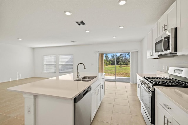 kitchen featuring light tile patterned flooring, sink, an island with sink, stainless steel appliances, and white cabinets