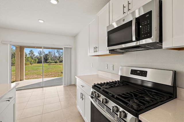 kitchen featuring appliances with stainless steel finishes, light tile patterned floors, and white cabinets