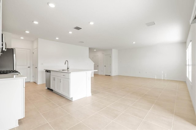 kitchen featuring sink, light tile patterned floors, appliances with stainless steel finishes, white cabinetry, and an island with sink