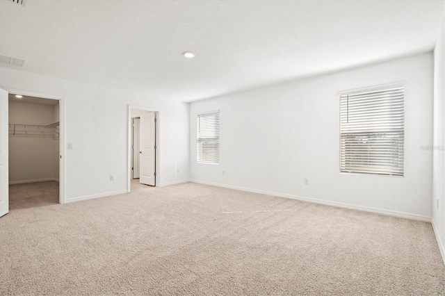 unfurnished bedroom featuring light carpet, a spacious closet, and a closet