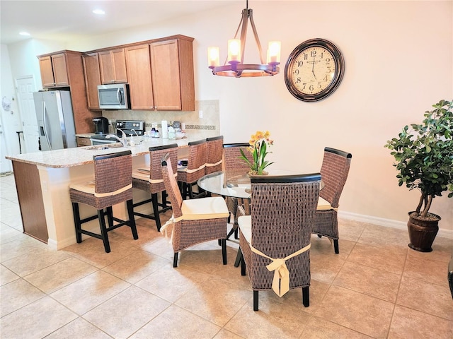 kitchen featuring tasteful backsplash, a chandelier, hanging light fixtures, light tile patterned floors, and appliances with stainless steel finishes