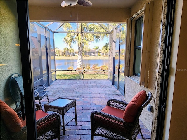 sunroom featuring ceiling fan and a water view