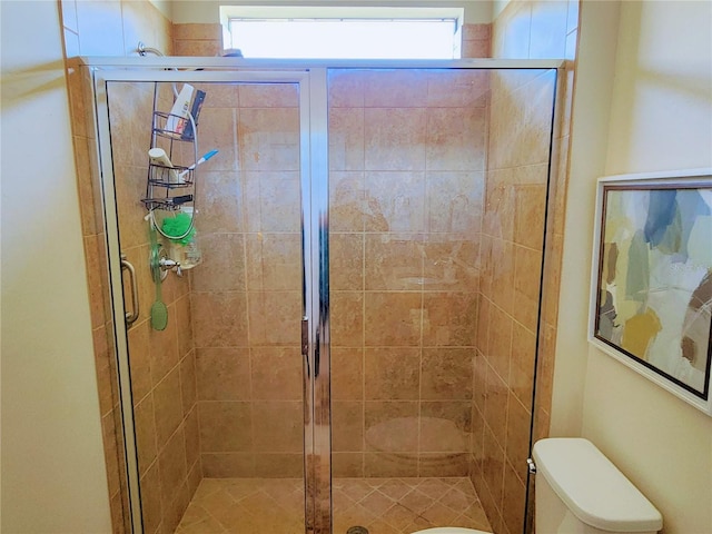 bathroom featuring a shower with door and toilet