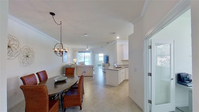 dining space featuring crown molding, sink, and an inviting chandelier