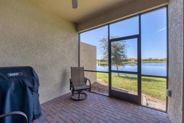 unfurnished sunroom featuring a wealth of natural light, ceiling fan, and a water view