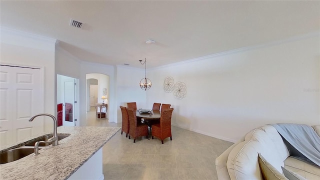 dining room featuring crown molding, sink, and a chandelier