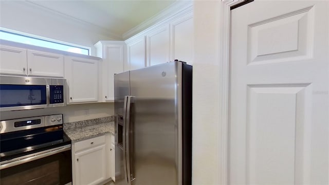 kitchen with white cabinetry, light stone counters, crown molding, and appliances with stainless steel finishes