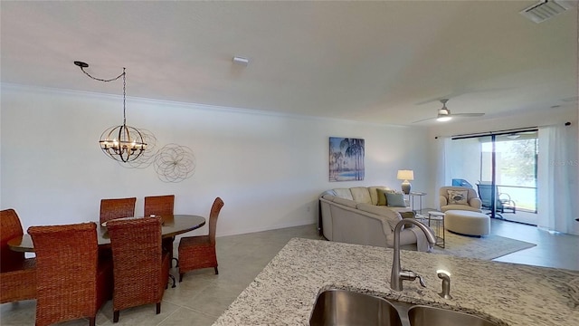 dining space featuring ceiling fan with notable chandelier, ornamental molding, and sink