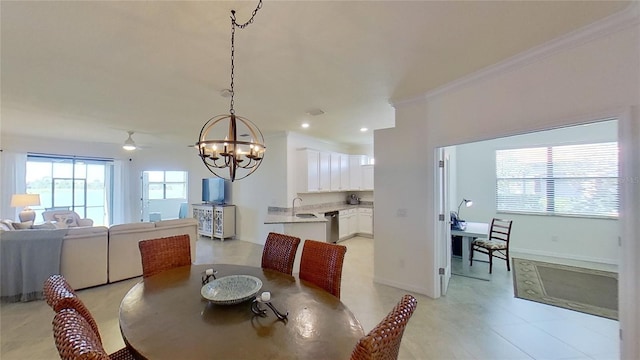 dining room featuring ceiling fan with notable chandelier, ornamental molding, and sink