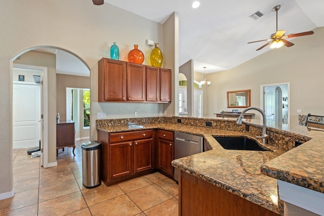 kitchen with stainless steel dishwasher, dark stone counters, sink, and light tile patterned floors