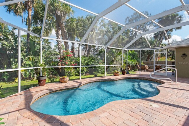 view of swimming pool featuring glass enclosure and a patio area