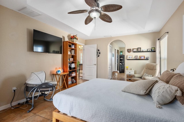 tiled bedroom featuring a tray ceiling and ceiling fan