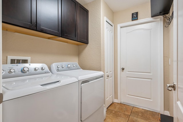 clothes washing area with cabinets, washer and dryer, and light tile patterned floors