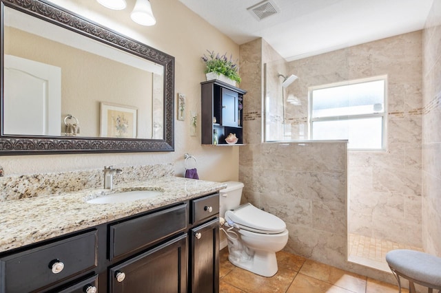 bathroom with vanity, tile patterned floors, toilet, and tiled shower