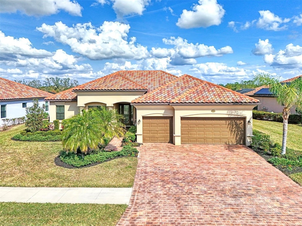 mediterranean / spanish home with a garage and a front lawn